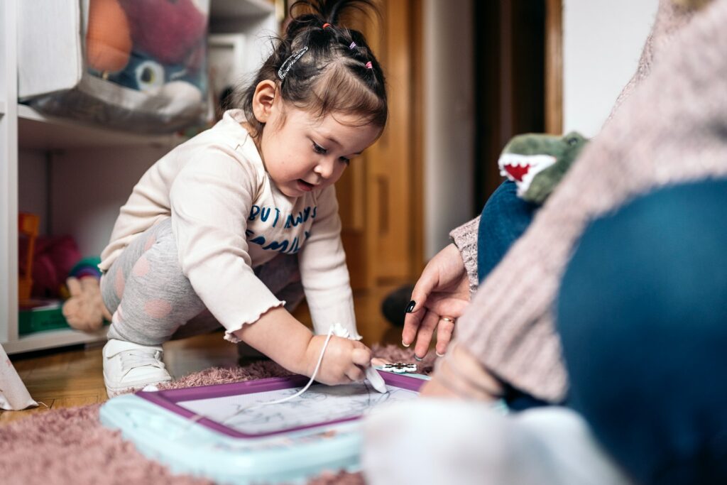 Une petite fille apprend à écrire sur une ardoise.