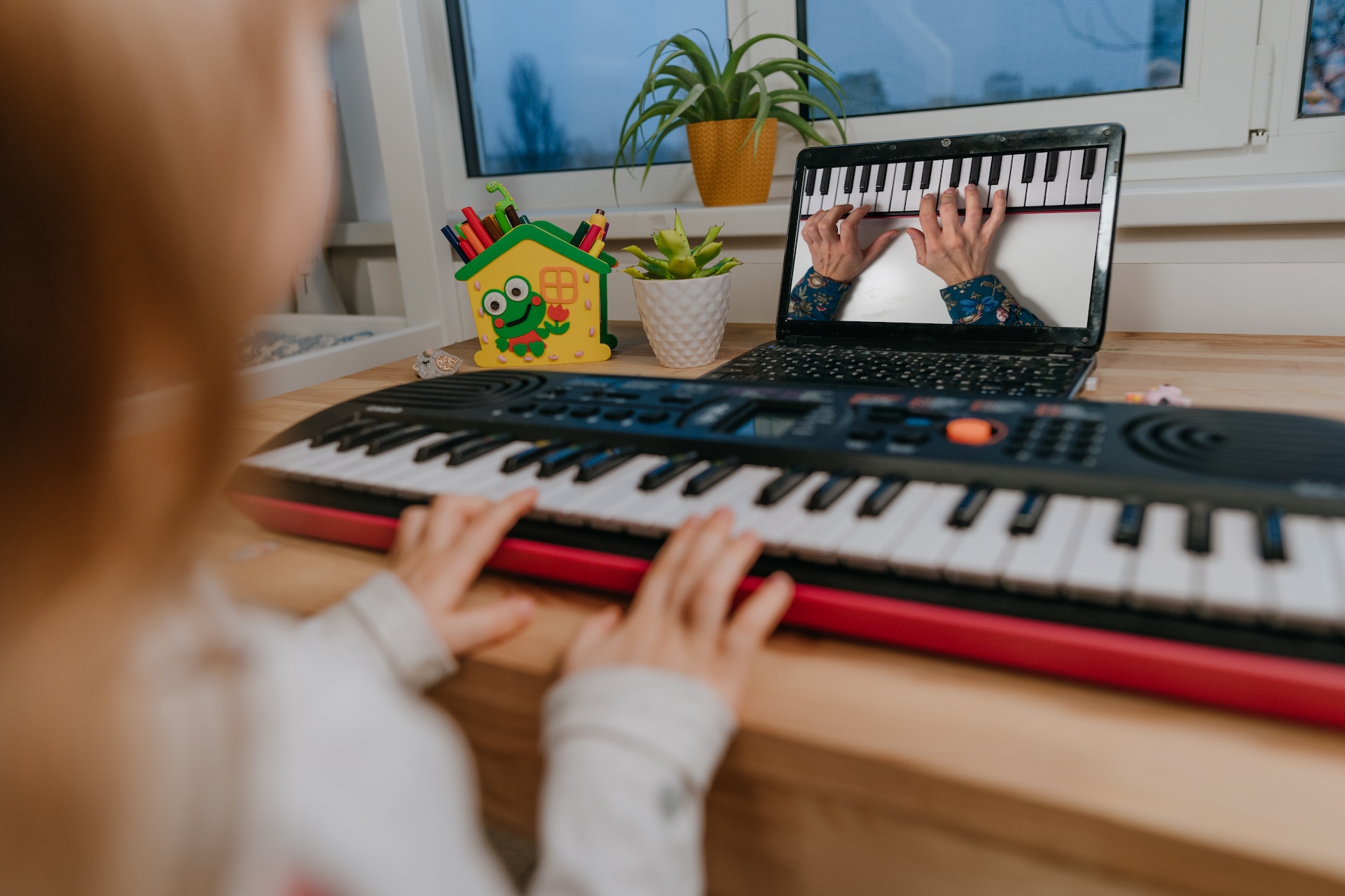 Une enfant travaille son piano devant une tablette.