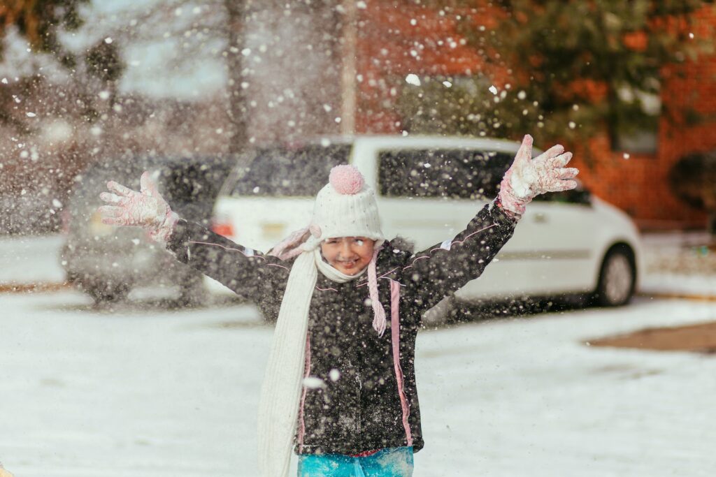 Une petite fille s'amuse dehors, sous la neige.