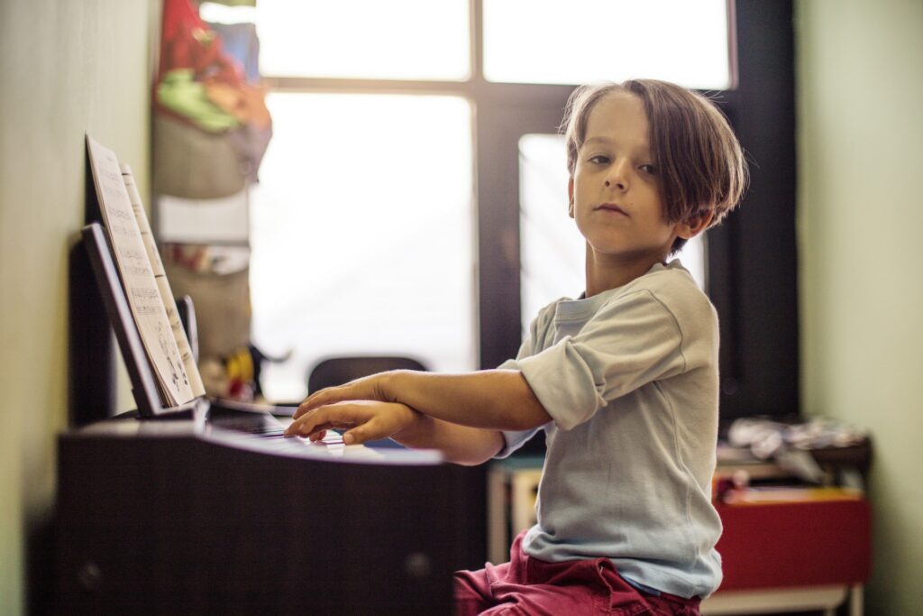 Un petit élève croise les mains sur un clavier de piano.