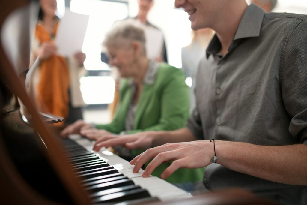 Un pianiste joue au clavier avec une personne âgée.