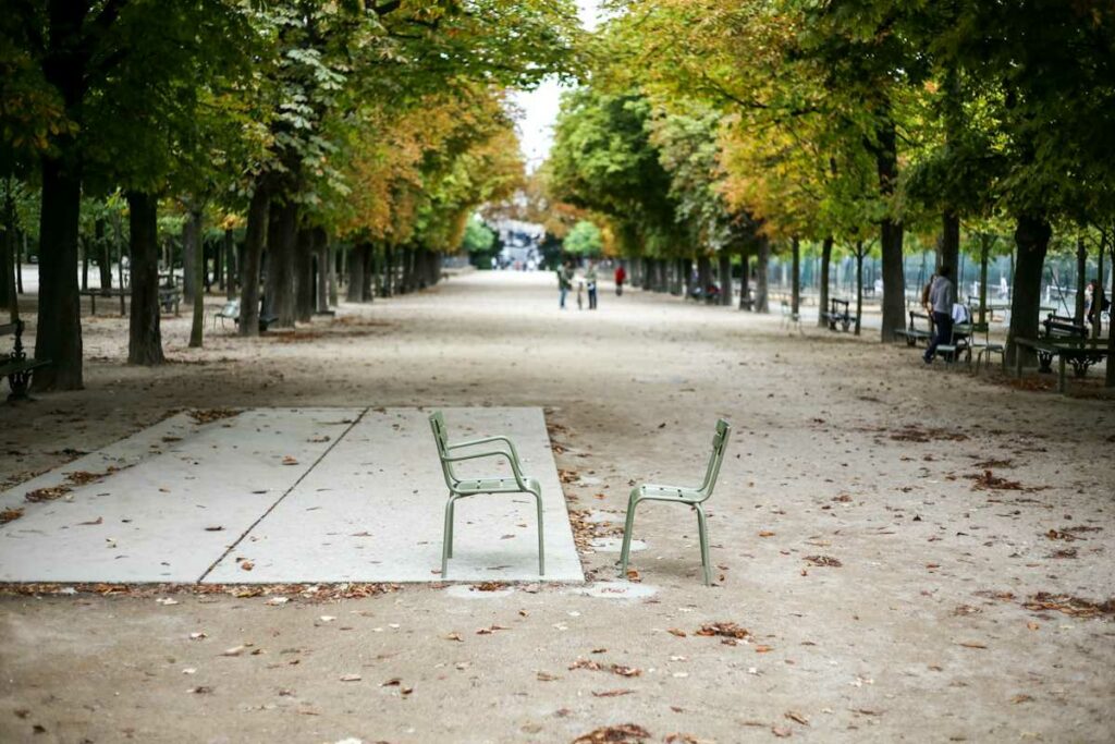 Un parc arboré dans une ville, avec des bancs pour s'asseoir et des allées pour marcher.