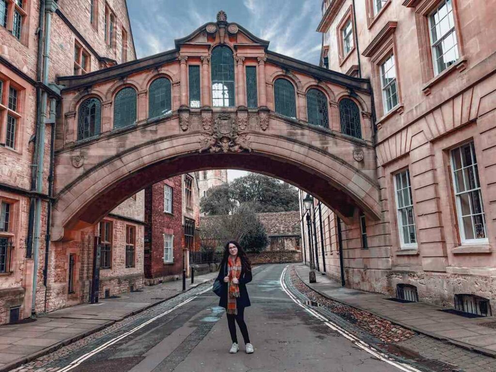 Une jeune femme se tient debout sous un pont célèbre au Royaume-Uni.