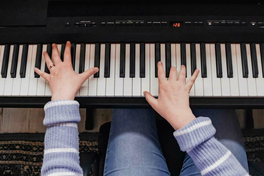 Une personne joue du piano devant une partition sur un instrument blanc.