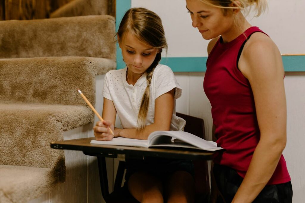 Une jeune fille travaille une leçon et une adulte supervise son travail.