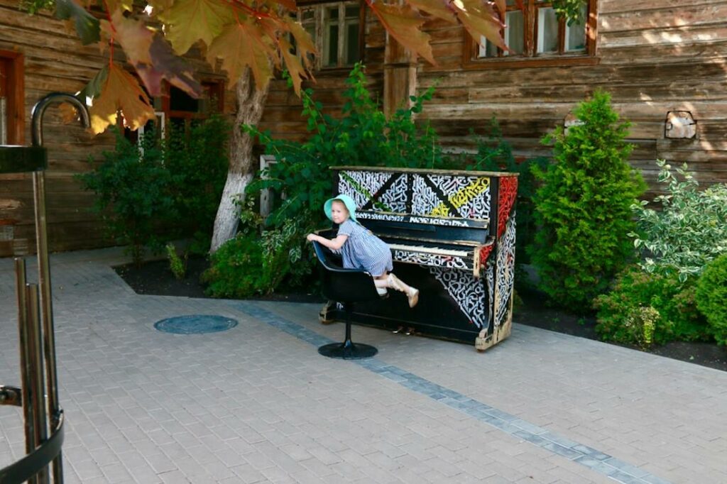 Un jeune petit garçon se tient mal assis sur un tabouret de piano.