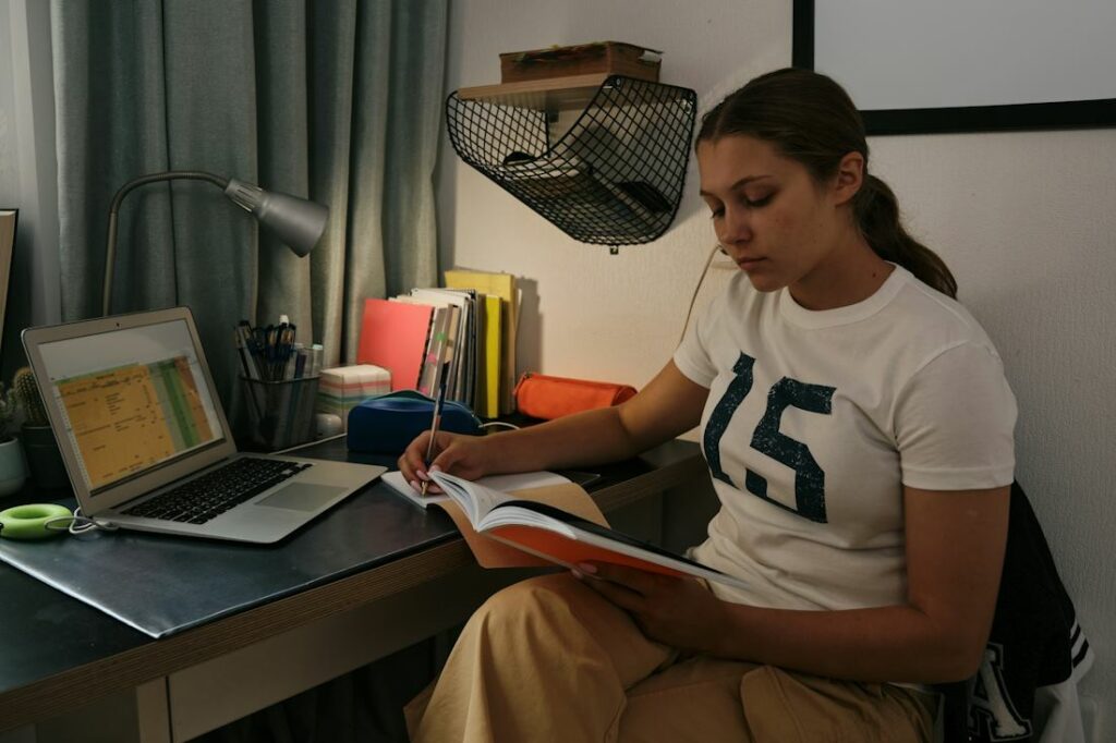 Une jeune dame en train de lire assise dans une pièce sombre, la nuit.