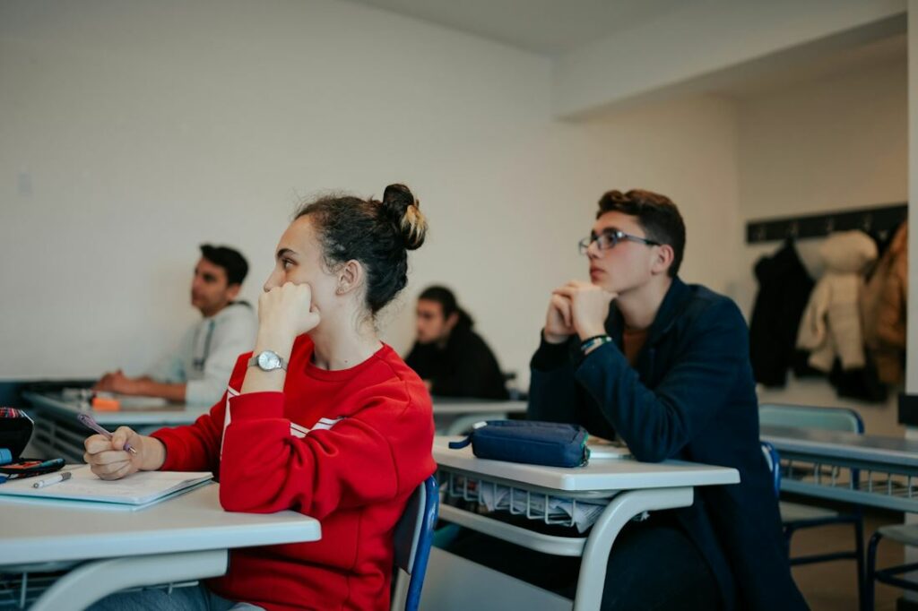 Des adolescents dans une salle de classe, écoutent leur professeur.