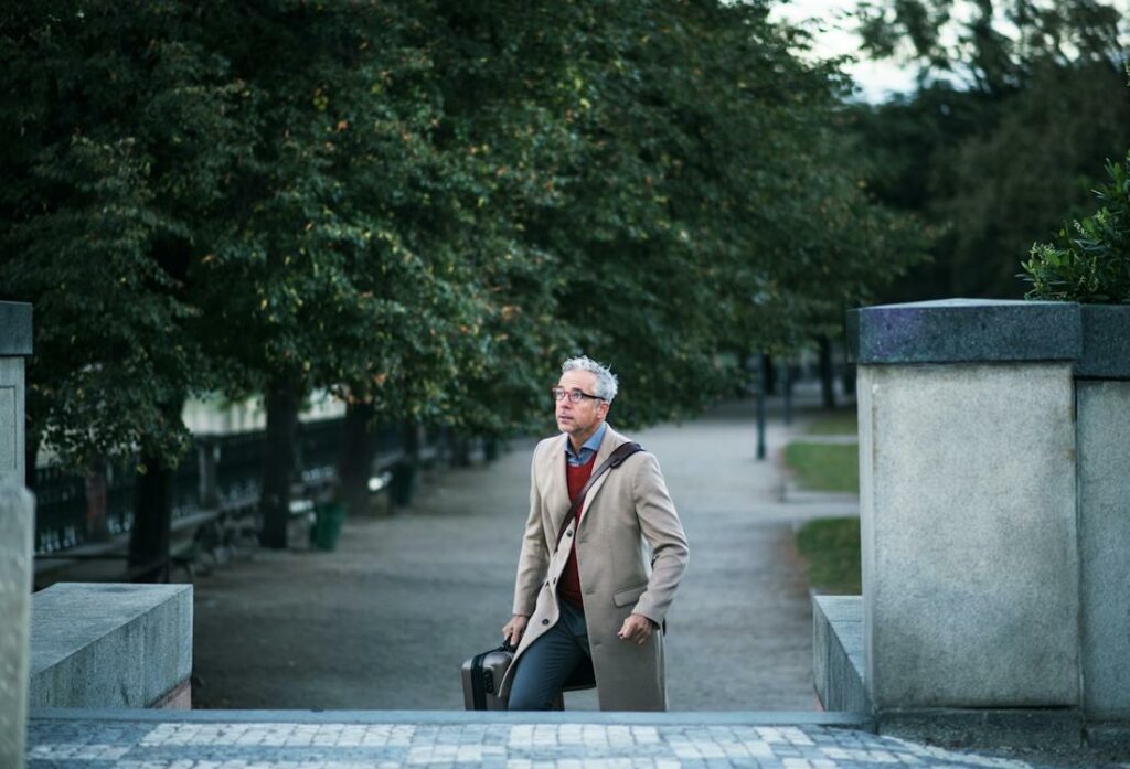 Un homme bien habillé marche dans un des parcs de Paris.