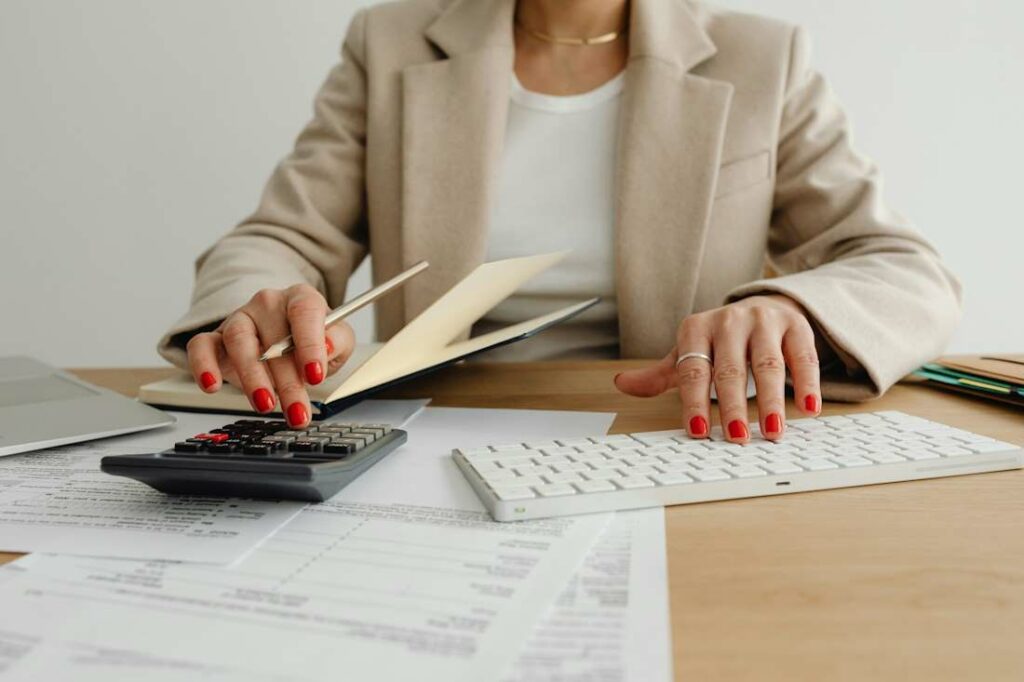 Une femme fait les comptes à l'aide d'une calculette en reportant les chiffres sur une feuille de papier.