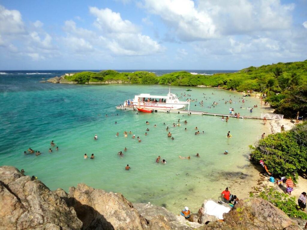 Vue sur une anse paradisiaque avec une mer turquoise et des gens qui se baignent.