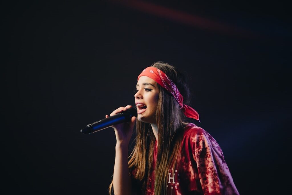 Photo d'une femme qui chante dans le micro, sur un fond noir.