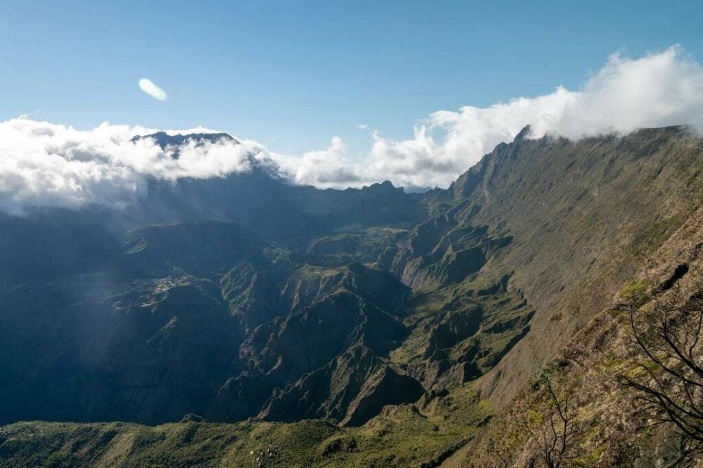 Vue depuis les pics vertigineux d'un massif aride avec quelques nuages.