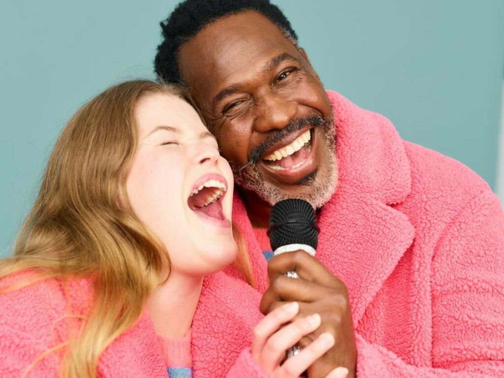 Deux personnes chantent en souriant avec un micro.