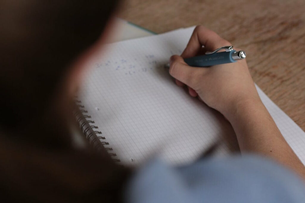 Une étudiante vue de dos en train de travailler sur une équation mathématique.