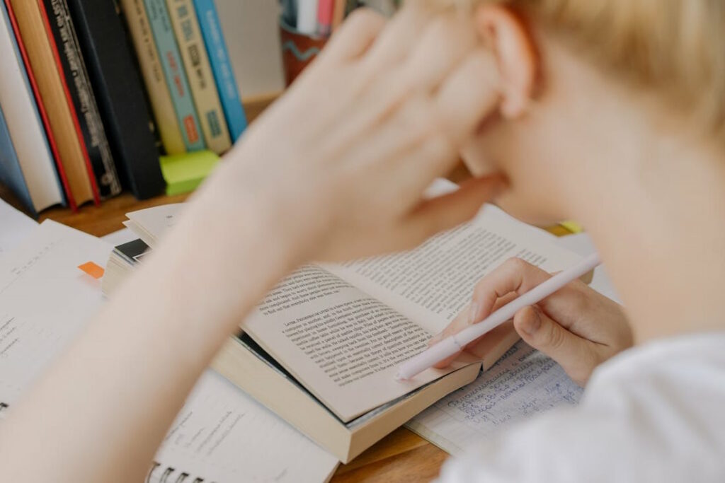 Un jeune homme vu de dos en train de lire un livre.