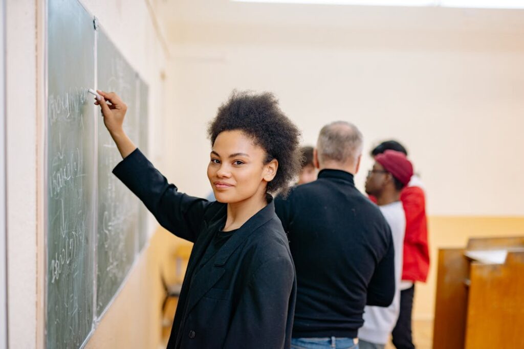 Une jeune femme écrit au tableau de sa salle de classe.