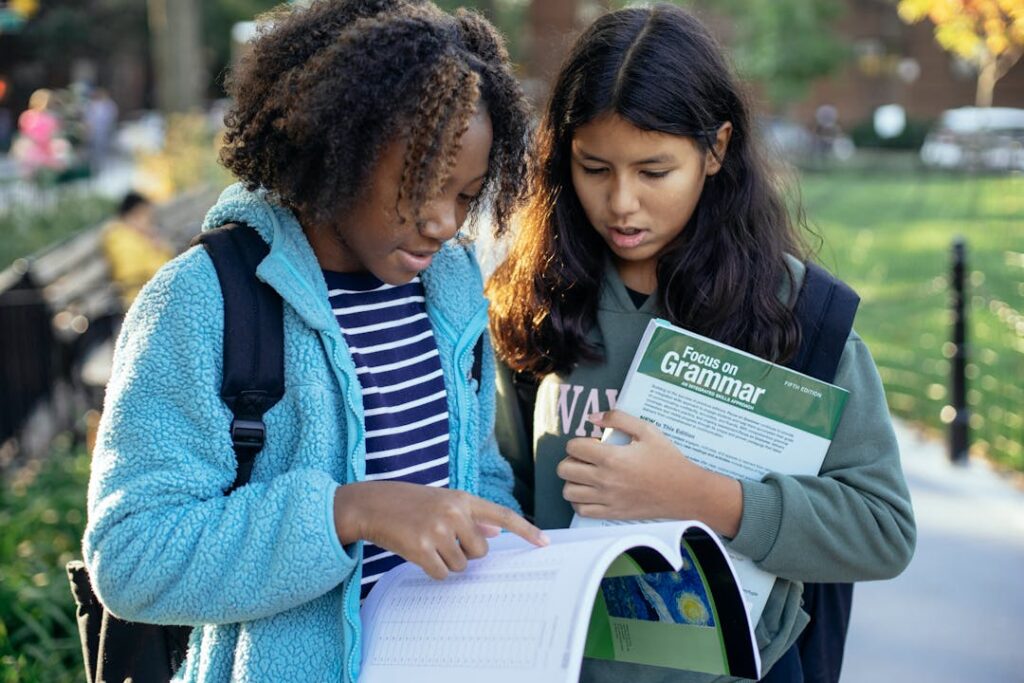 Deux élèves lisent un cahier avec un livre en anglais.