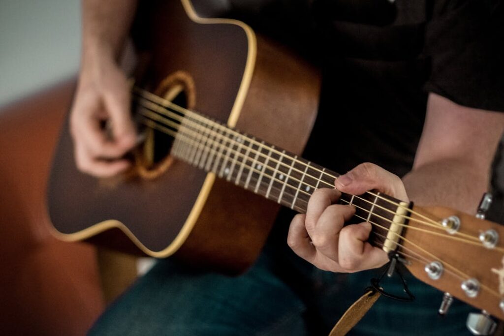 Un guitariste est en train de jouer un accord de base en position ouverte sur les cases 1, 2 et 3.