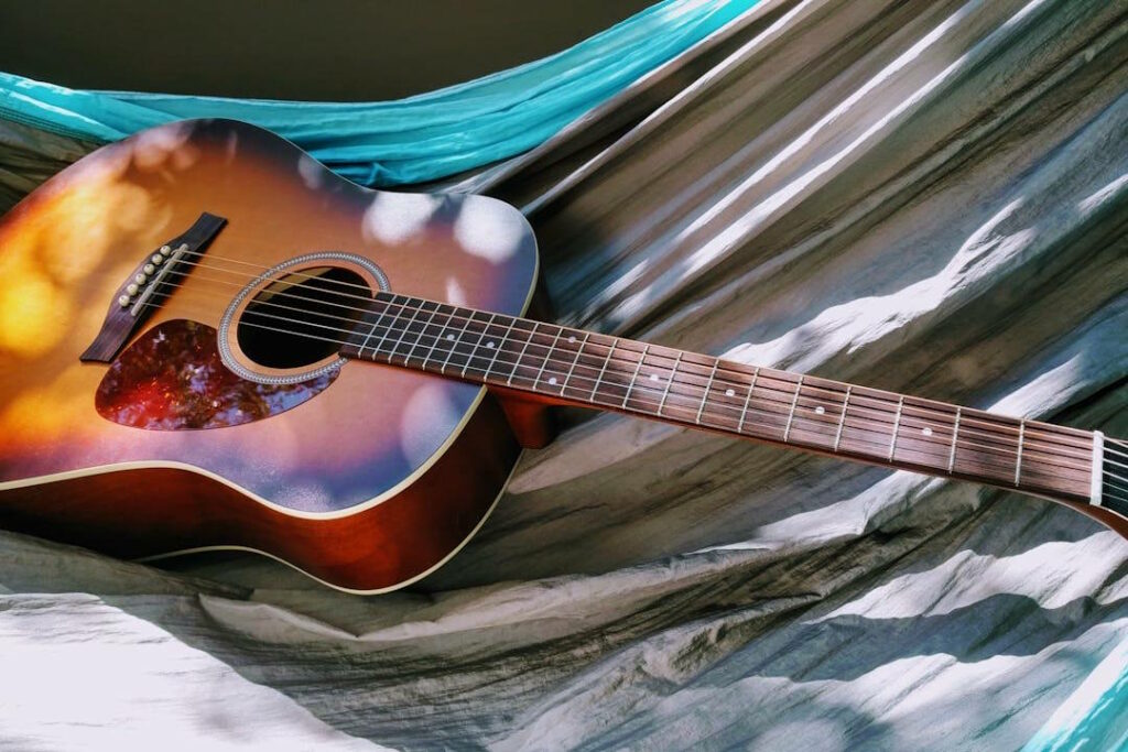 Une guitare acoustique est posée sur un lit suspendu en toile.