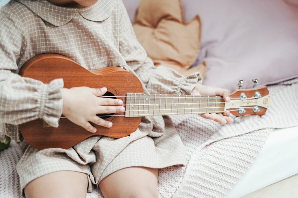 Un tout petit enfant avec une petite guitare à 4 cordes.