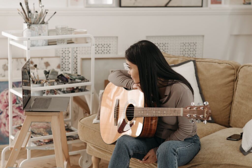 Une femme assise sur un canapé joue de la guitare.