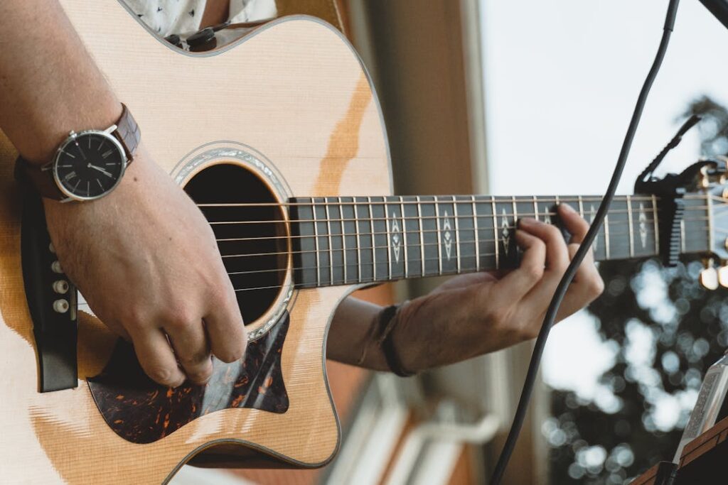 Vue rapprochée sur un homme en train de jouer sur une guitare acoustique.