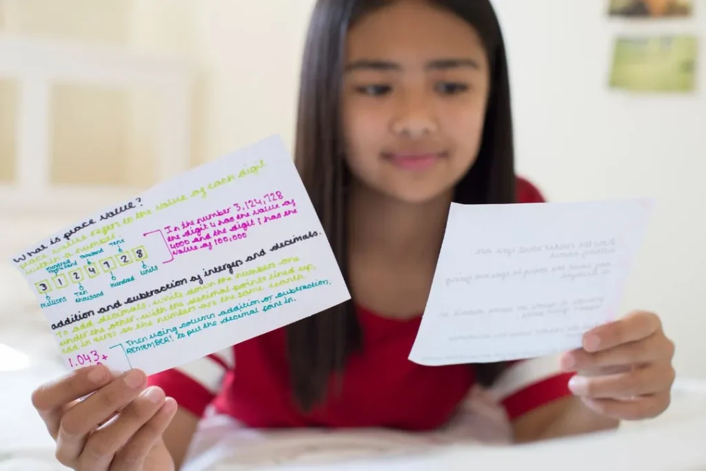 Une jeune femme est en train de réviser avec des fiches mémo rédigées en anglais.