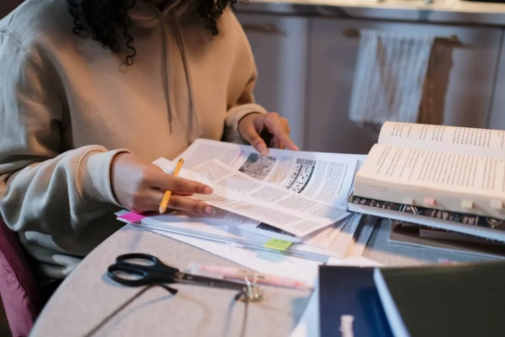 Une jeune femme est en train de travailler à ses devoirs sur un bureau.