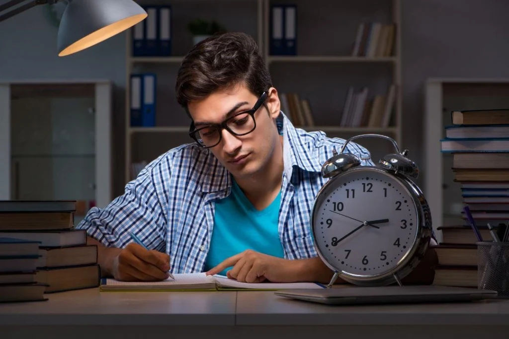 Un garçon fait un devoir sur table en contrôlant l'heure.