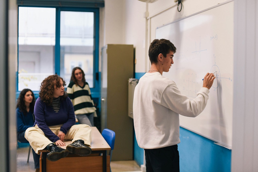 Un élève fait un exercice devant ses camarades au tableau.