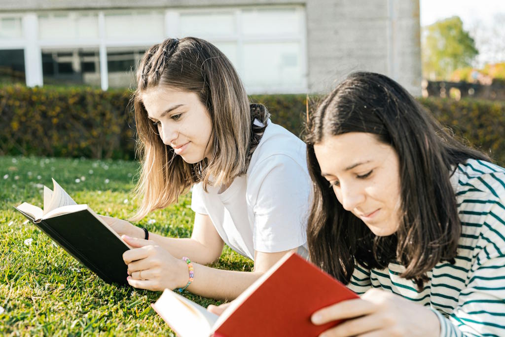 Deux jeunes femmes sont allongées et lisent dans l'herbe.