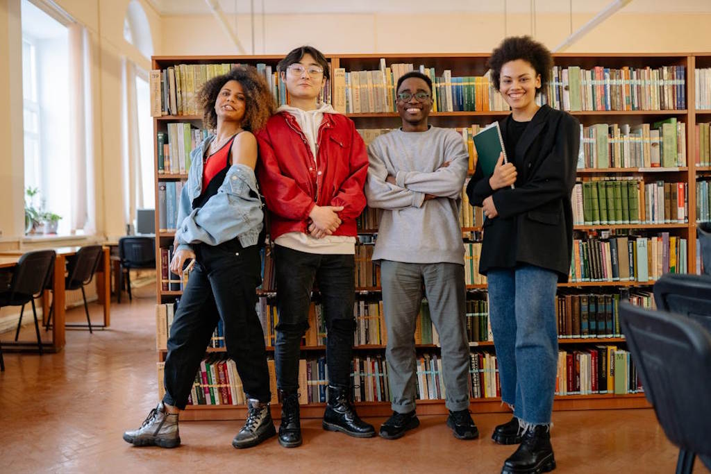 Quatre jeune adolescents sourient devant une bibliothèque.