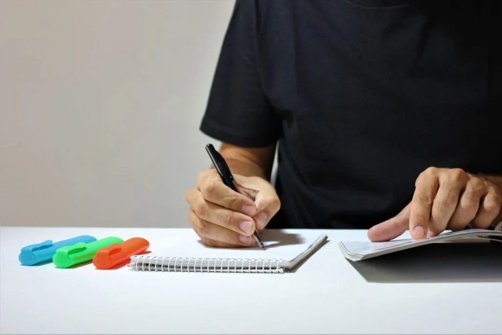 Un garçon est en train de recopier un texte sur une feuille.