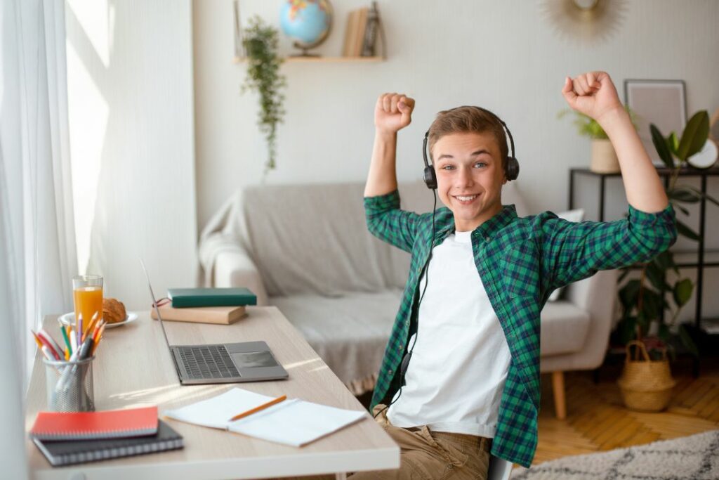 Un jeune adolescent lève les bras en l'air car il est content.