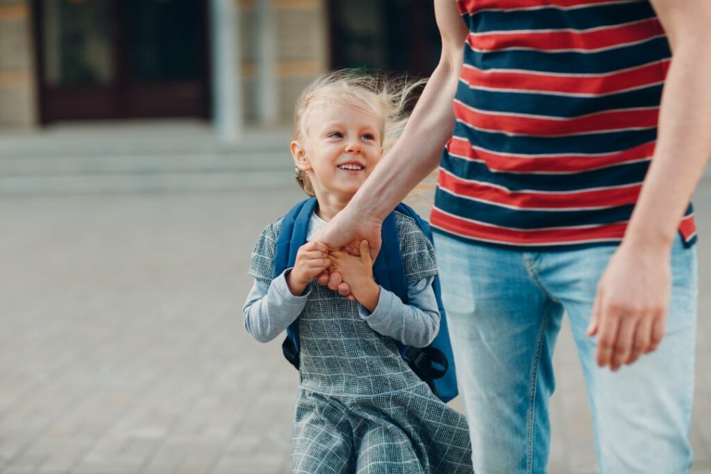 Une petite fille tient la main de son père.