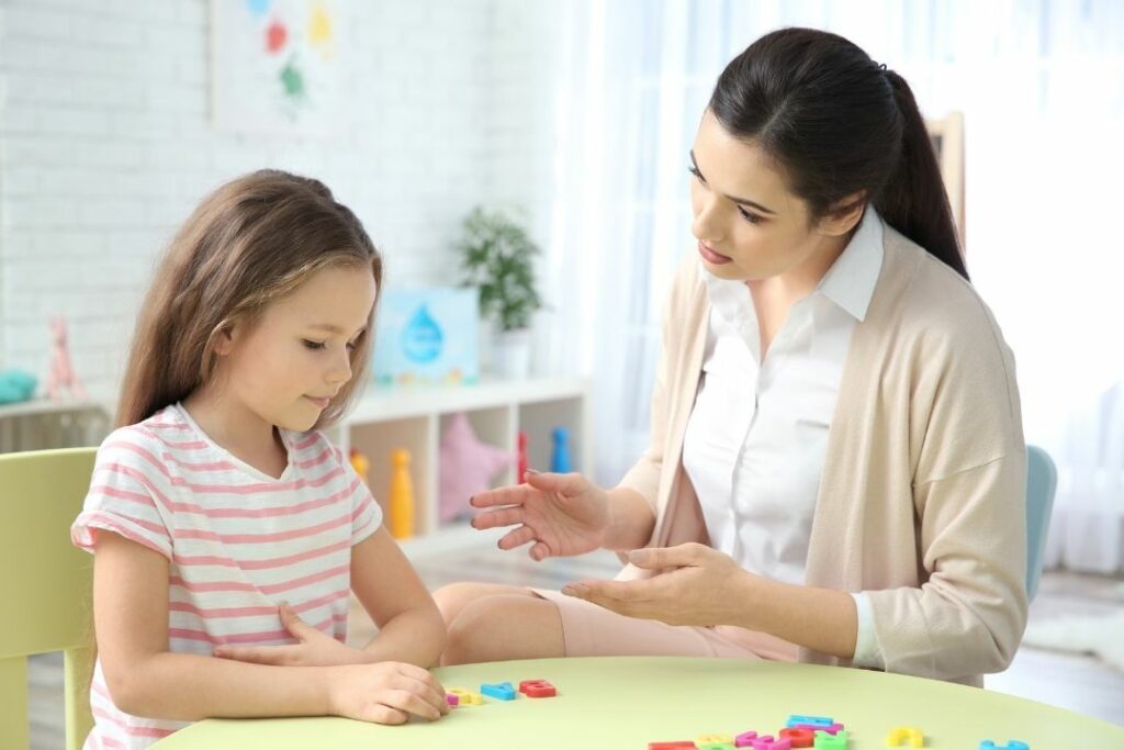 Une femme donne un cours de français à une petite fille.
