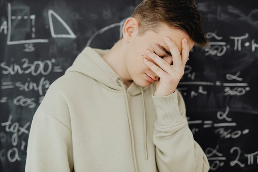 Un ado devant un tableau noir plein de formules mathématiques.