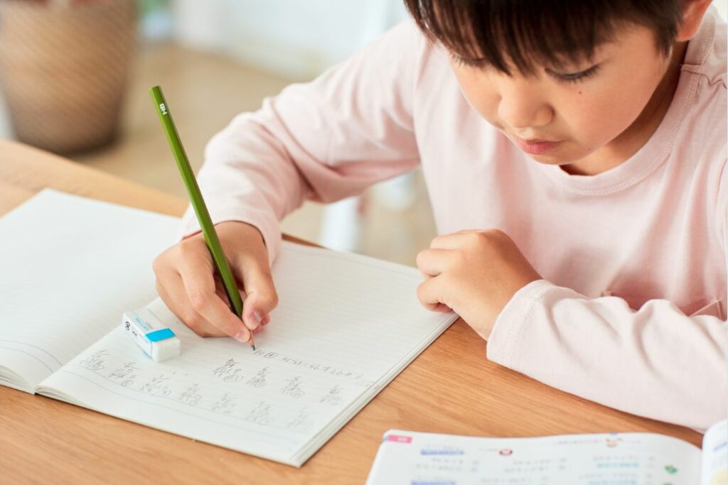 Un écolier travaille à ses devoirs sur table.