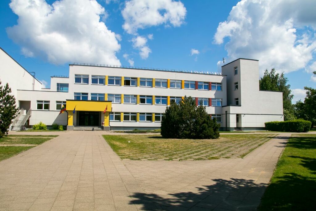 Vue de l'extérieur d'un établissement scolaire blanc avec entrée jaune.