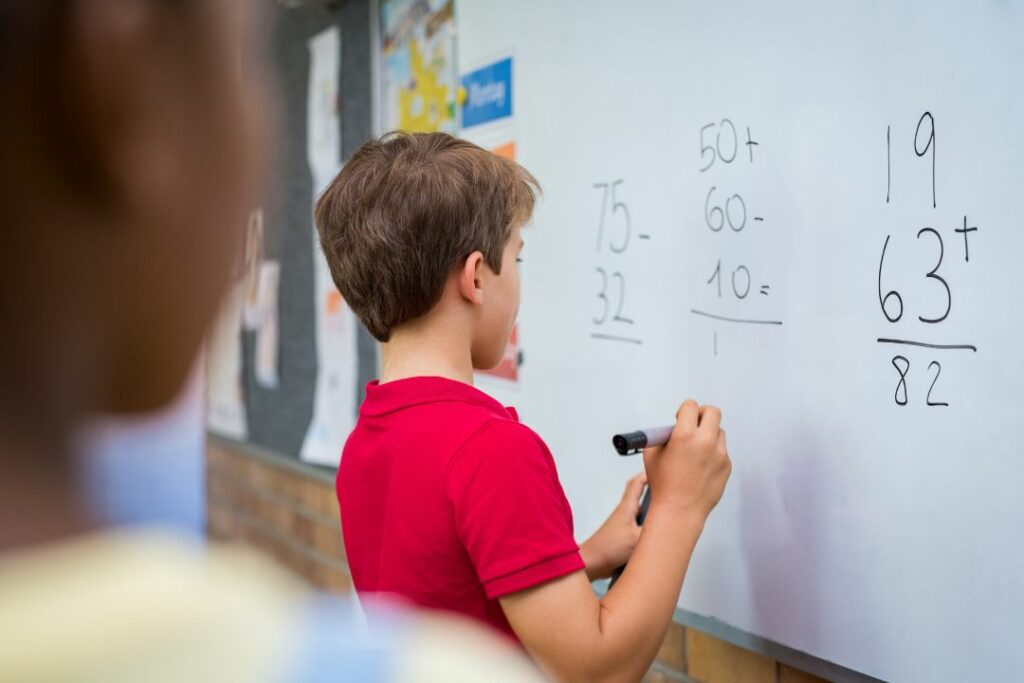 Un petit garçon effectue une opération mathématique en classe.