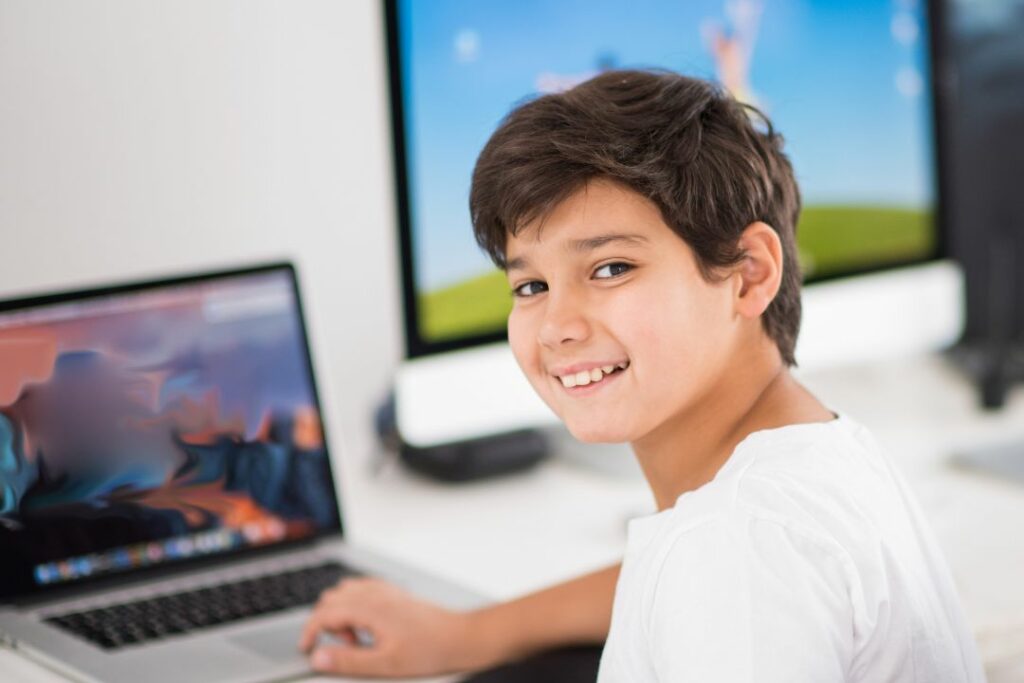 Un garçon devant un PC portable.