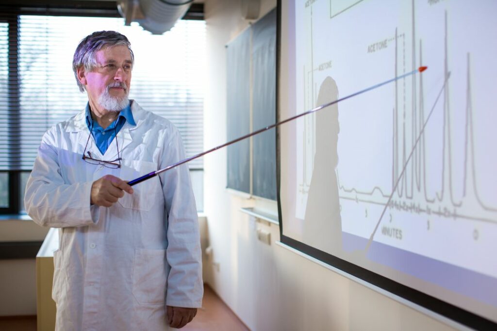 Professeur en blouse blanche expliquant un graphique de chromatographie lors d'un cours de physique chimie.