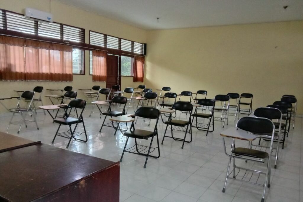 Une salle de classe vide avec des chaises d'examen rangées.
